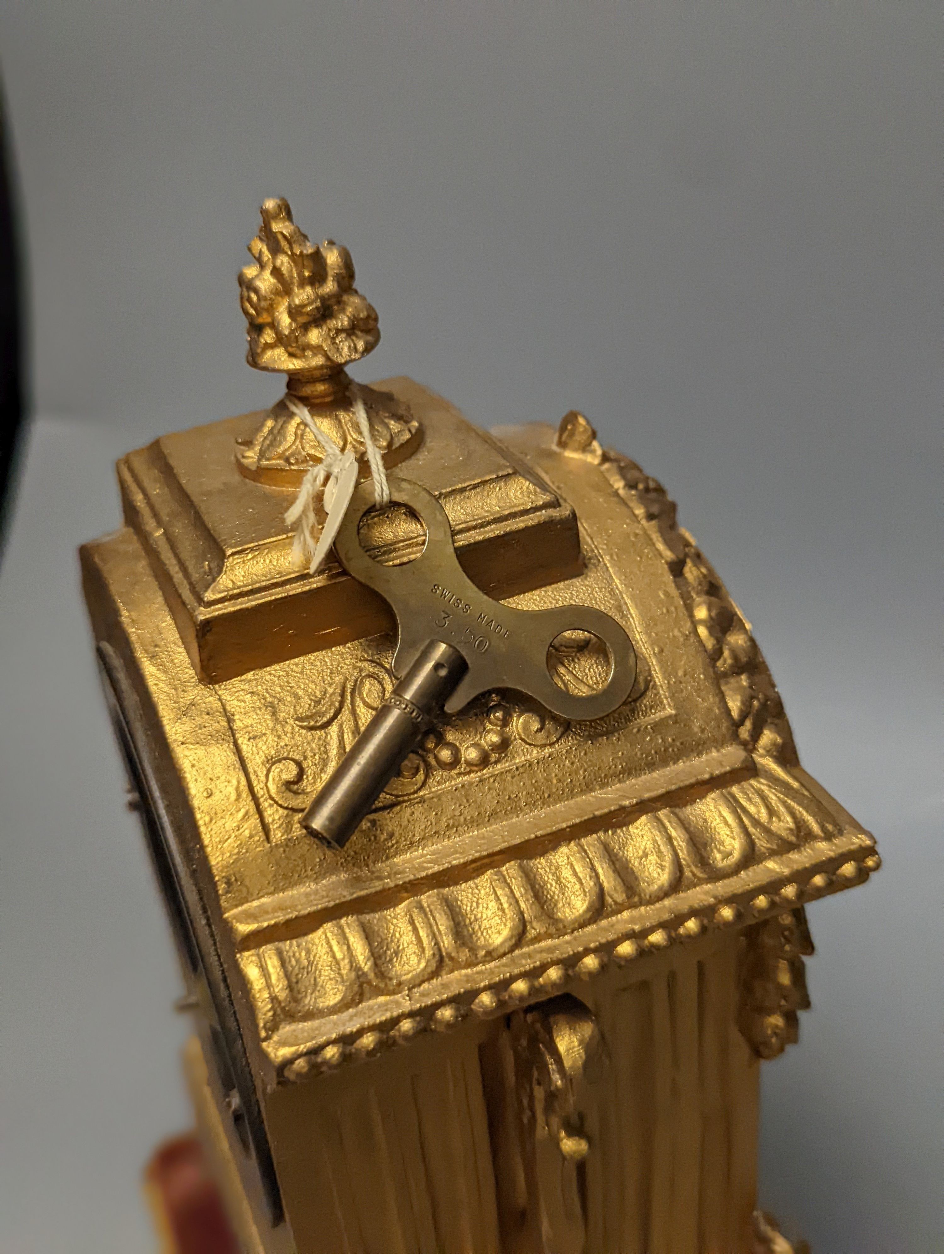 A 19th century gilt metal mantel clock on plinth with key and pendulum 30cm